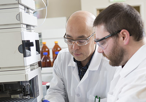 Dr. Lee (left) and Lab Assistant Zack Cizek prepare equipment for a pharmaceutical product manufacturing lab.
